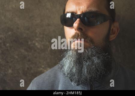 A man with a long beard on the background of the dark wall Stock Photo