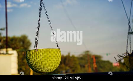 Hanging yellow color plastic pot in the house. Pot without plants in outdoor garden Stock Photo
