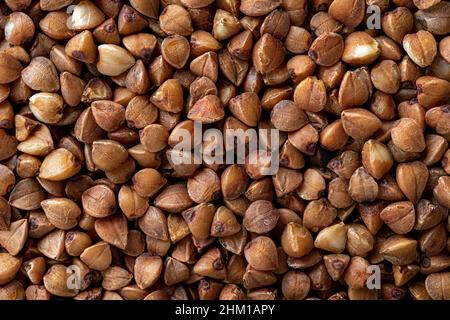 Organic buckwheat groats macro background. Roasted dry buckwheat grains texture close-up. Wholegrain buckwheat seeds for gluten free diet, vegetarian Stock Photo