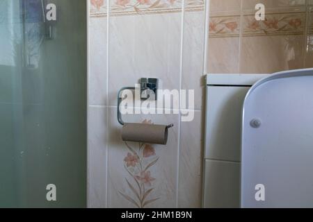 Empty Toilet roll cardboard tube on metal loo roll holder. Stock Photo