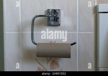 Empty Toilet roll cardboard tube on metal loo roll holder. Stock Photo