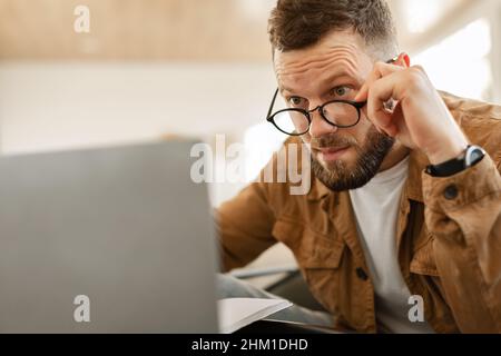 Shocked Freelancer Man Looking At Laptop Above Eyeglasses Indoor Stock Photo