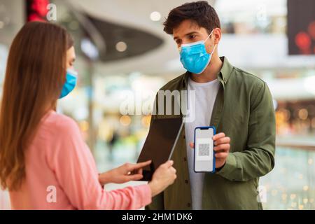 Man Showing Smartphone With QR Code To Woman In Hypermarket Stock Photo