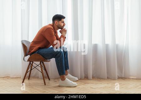 Pensive Arab man sitting on chair and thinking Stock Photo