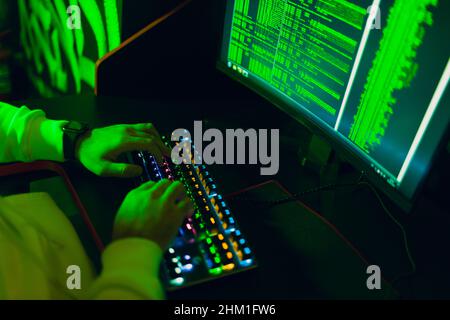 Hacker using computer malware software and hacking binary code green digital interface hands keyboard close up Stock Photo