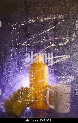 View through dirty glass. Close-up of household cleaning products and kitchen accessories. On a dark lilac background. High quality photo Stock Photo