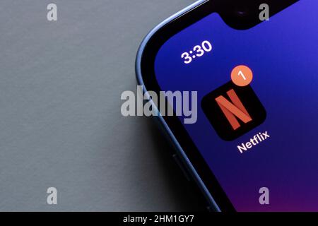 Netflix app icon is seen on the screen of an iPhone. Stock Photo