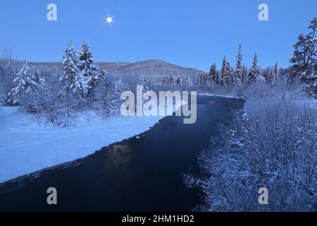 Yaak River and moon at dawn in winter. Yaak Valley, northwest Montana. (Photo by Randy Beacham) Stock Photo