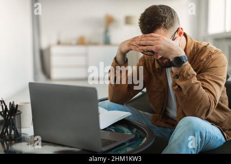 Stressed Man At Laptop Touching Head Having Business Problems Indoor Stock Photo