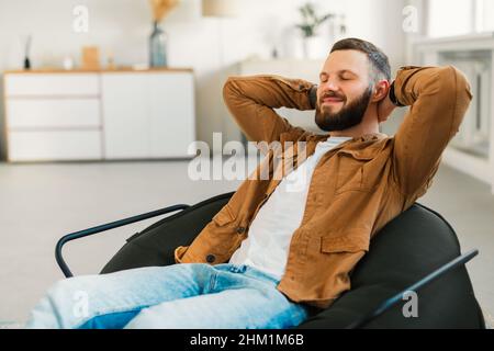 Relaxed Bearded Man Resting With Eyes Closed Sitting At Home Stock Photo