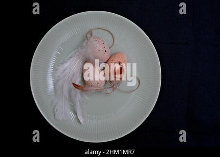 Brown Easter eggs and white feathers on a greenish plate Stock Photo
