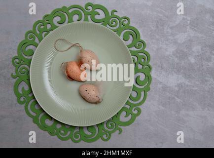 Three Easter eggs on a greenish plate and decorative tablet Stock Photo
