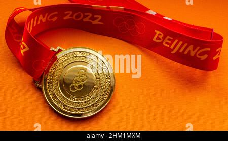 January 27, 2022, Beijing, China. XXIV Olympic Winter Games gold medal on an orange background. Stock Photo