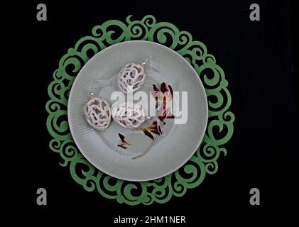 Three white easter eggs and faded tulip petals on a greenish plate Stock Photo