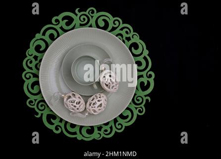 Three white easter eggs and an empty coffee cup on a greenish plate Stock Photo