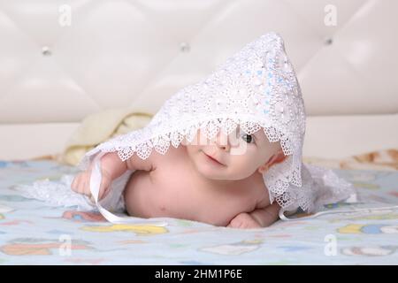 The newborn baby looks into the camera while lying on the stomach Stock Photo