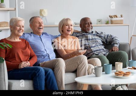 Multiracial friends senior people watching TV in the living room Stock Photo