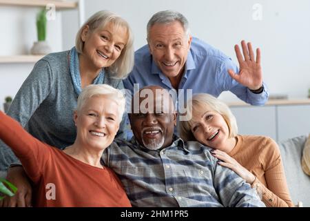 Happy elderly people taking selfie together, home interior Stock Photo