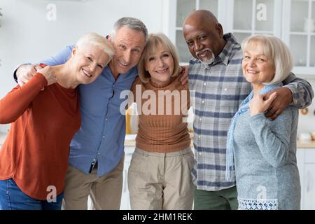 Group photo of happy elderly people hugging, smiling at camera Stock Photo