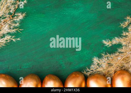 Golden Easter eggs and golden branches, reeds on a green watercolor background. Banner. Layflat. Space for text Stock Photo