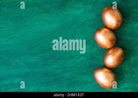 Golden Easter eggs and golden branches, reeds on a green watercolor background. Banner. Layflat. Space for text Stock Photo