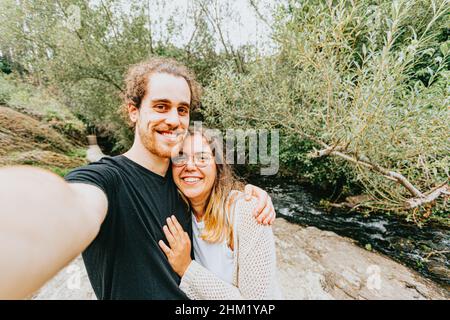 A young spanish couple taking a lovely selfie in the shore of a river Stock Photo