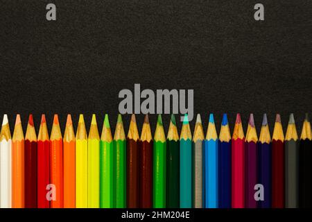 Colorful pencils lined up over a dark background Stock Photo