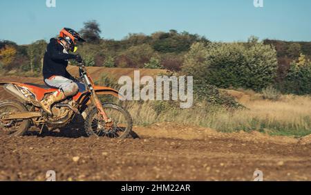 Motocross enduro rider accelerating in dirt track Stock Photo