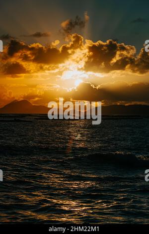 A massive sunset between the clouds with some islands over the ocean Stock Photo