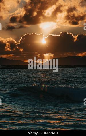 A massive sunset between the clouds with some islands over the ocean Stock Photo