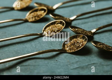 A group of golden spoons with tea over a blue background Stock Photo