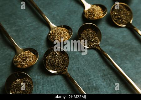 A group of golden spoons with tea over a blue background Stock Photo