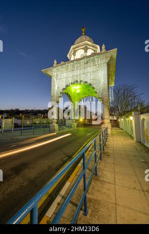 The entrance gate to the Sikh temple Siri Guru Nanak Darbar Gurdwara Gravesend Kent at night Stock Photo