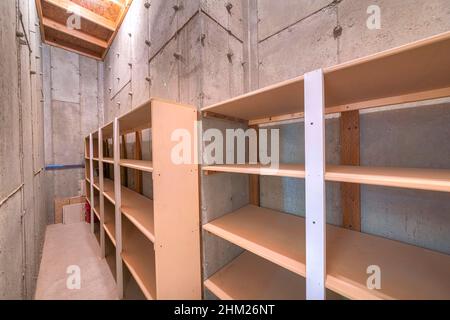 Unfinished narrow storage room with concrete walls and floors Stock Photo