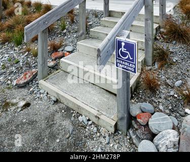 Disabled parking wheelchair sign beside stairs to restrooms. Stock Photo