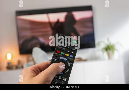 Male hand holding TV remote control and Watch tv Stock Photo