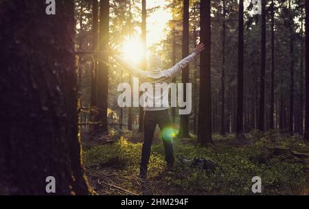 Man praying at sunset in the deep woods raised hands Stock Photo