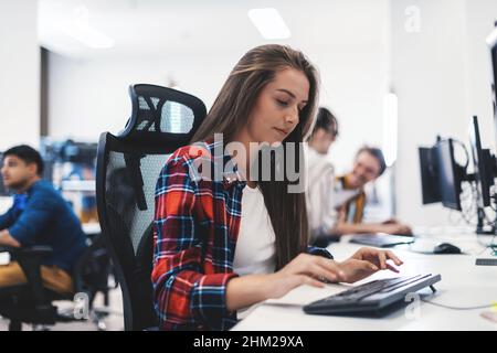 Casual business woman working on desktop computer in modern open plan startup office interior. Selective focus  Stock Photo