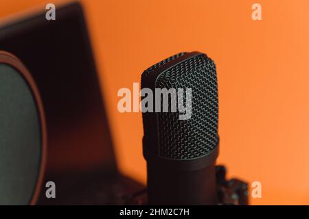 Close up mock up of a streaming microphone with a laptop over an orange background with copy space, minimal concept, technology streaming Stock Photo
