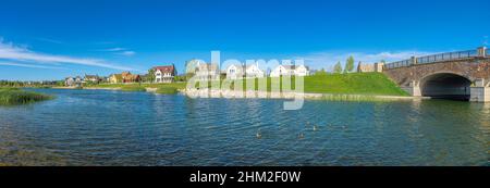 Panoramic view of Oquirrh Lake with grassy shore and stone bridge on the left Stock Photo