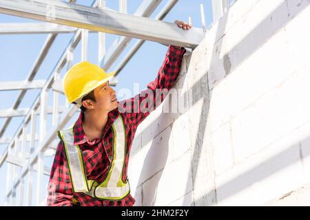 Construction worker or contractor checking house frame, worker roofer builder working on steel roof structure on building  construction site Stock Photo