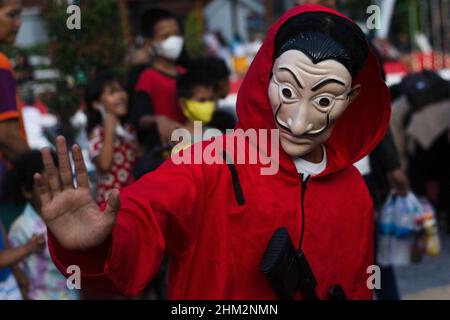 Palembang, South Sumatra, Indonesia. 7th Feb, 2022. The people of Palembang city wear Red Jumpsuits and wear the Salvador Dali masks from the Money Heist Serial character to entertain visitors at one of the tourist attractions in the city of Palembang, South Sumatra. Behind the costumes and colors have meaning, the red jumpsuit was also chosen because red is a symbol for revolution and has been used by many resistance groups throughout history. Meanwhile, the meaning of the masks is in addition to maintaining their original identity. Credit: ZUMA Press, Inc./Alamy Live News Stock Photo