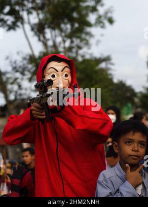 Palembang, South Sumatra, Indonesia. 7th Feb, 2022. The people of Palembang city wear Red Jumpsuits and wear the Salvador Dali masks from the Money Heist Serial character to entertain visitors at one of the tourist attractions in the city of Palembang, South Sumatra. Behind the costumes and colors have meaning, the red jumpsuit was also chosen because red is a symbol for revolution and has been used by many resistance groups throughout history. Meanwhile, the meaning of the masks is in addition to maintaining their original identity. Credit: ZUMA Press, Inc./Alamy Live News Stock Photo