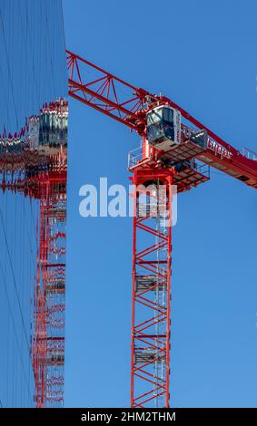 Denver, Colorado - January 29, 2022. Tower crane from the construction site with the reflection in the nearby glass facade Stock Photo