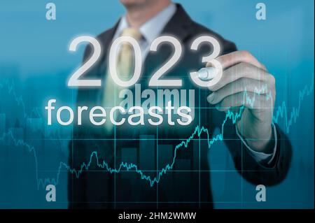 Economic forecasts for 2023. businessman writes forecasts for 2023 on virtual screen. Post covid-19 economy recovery. Businessman in suit forecast ana Stock Photo