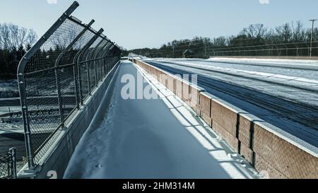 Frozen snow covered overpass. The road and highway covered in fresh snow. Perspective view walking across the sidewalk over the highway. Stock Photo