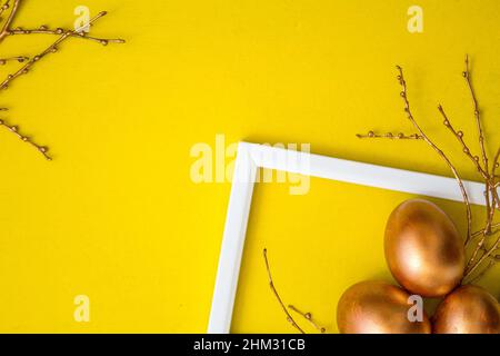 Golden Easter eggs and golden branches on a yellow watercolor background. Banner. Layflat. Space for text Stock Photo