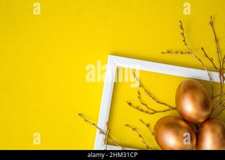 Golden Easter eggs and golden branches on a yellow watercolor background. Banner. Layflat. Space for text Stock Photo