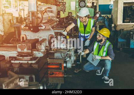 Engineer man and woman team work working together service fix check machine in factory Stock Photo