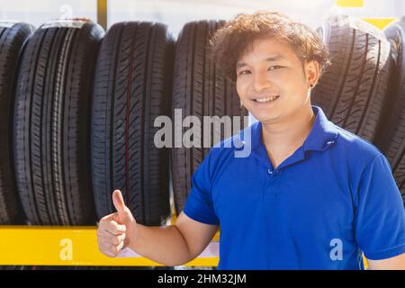 Car tire on shelf with salesman sale agent happy to service in tyre shop. Good quality vehicle tire, people recommended and promotion. Stock Photo